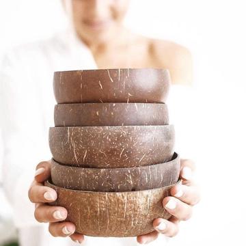 Stacked sustainable coconut bowls held in hands, highlighting eco-friendly design.